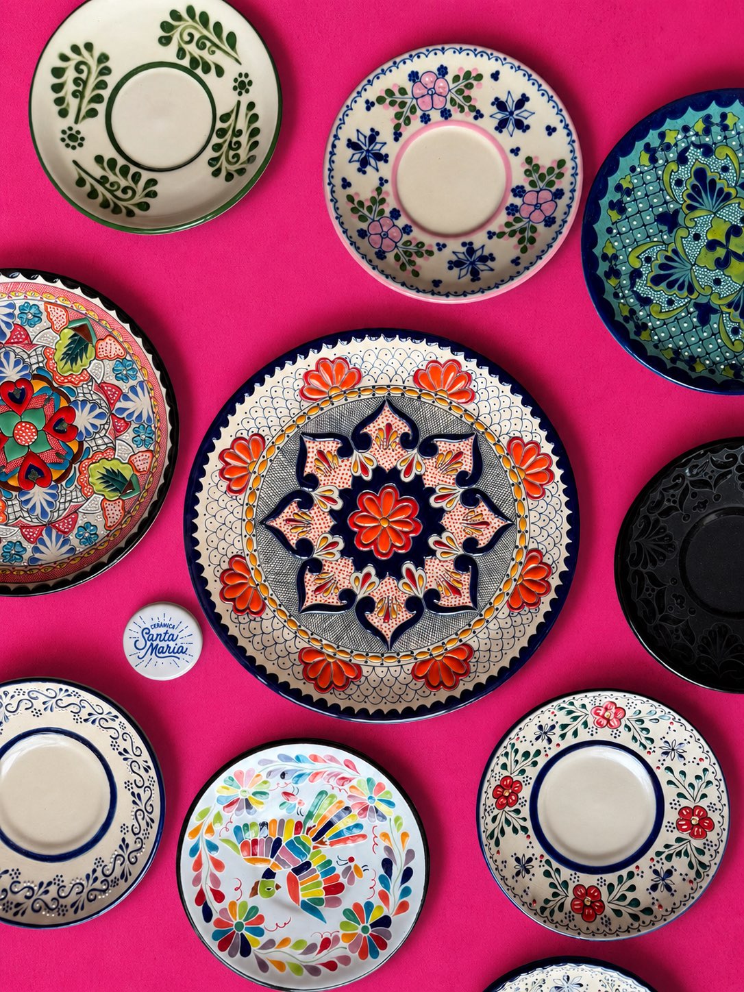 Platos de cerámica pintados a mano sobre fondo rosa mexicano
